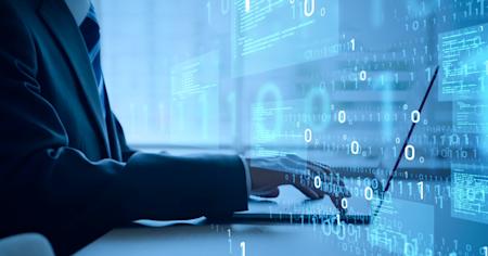 Business professional working on a laptop with digital code and cybersecurity graphics overlay.