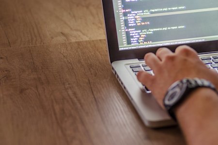 A hand typing on a laptop keyboard.