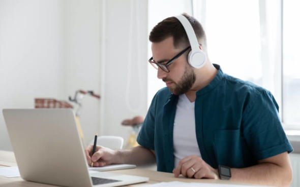 A man wearing headphones working on a Macbook to use Splashtop remote desktop software.