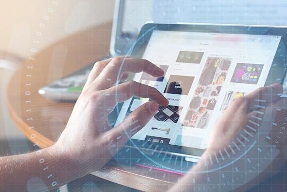 A person uses a tablet with both hands, browsing through images or products. A laptop is visible in the background, and a light, futuristic digital overlay surrounds the scene.
