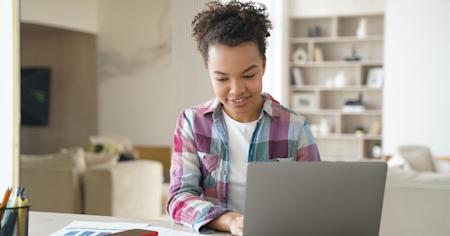A young woman working on a laptop during a remote session at a desk.