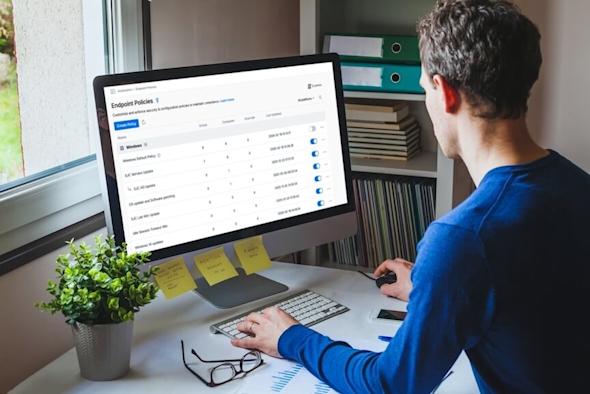 A person is using a desktop computer displaying the Splashtop management dashboard, specifically the Endpoint Policies section with various policy settings and options visible on the screen.