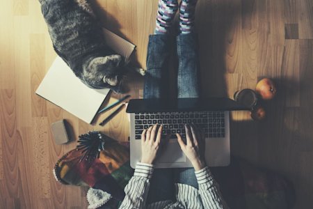 IT helpdesk manager sitting on the floor with a cat, researching remote access software for businesses