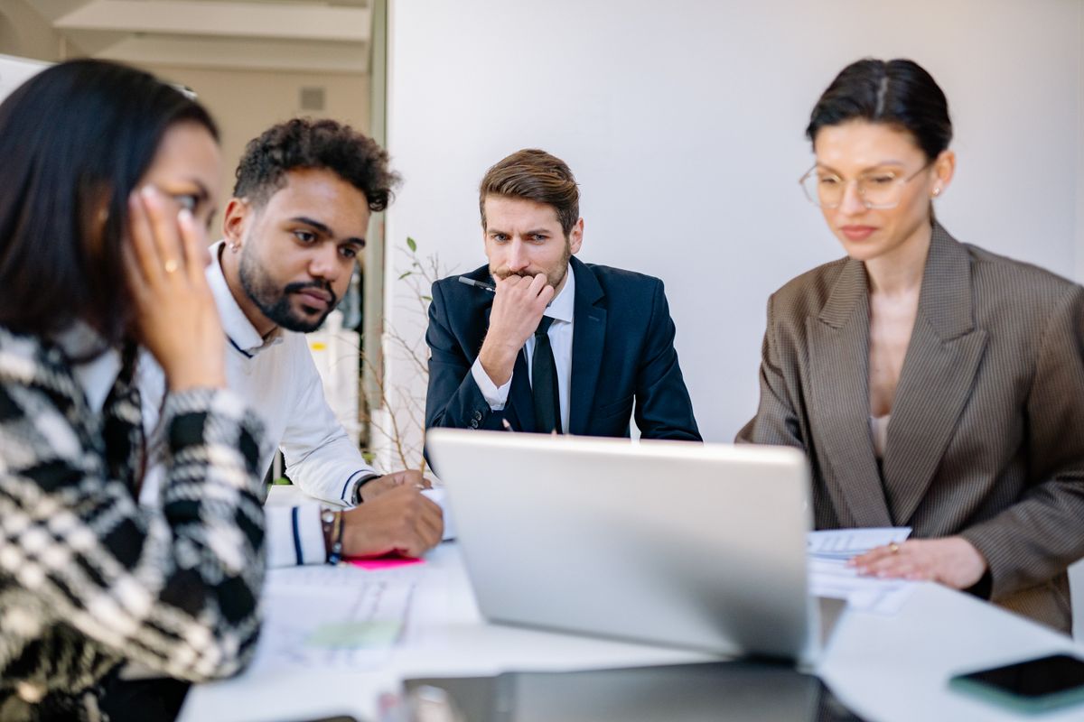 A group of people in a business office looking at a computer screen.