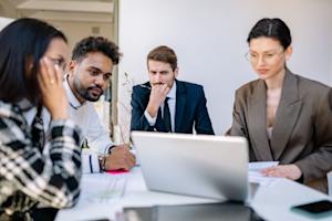 A group of people in a business office looking at a computer screen.