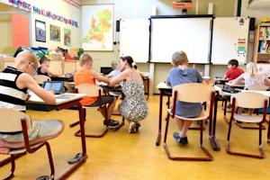 Classroom with students using tablets and a teacher assisting
