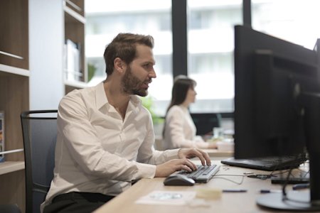 Two people working on their computers in an office.
