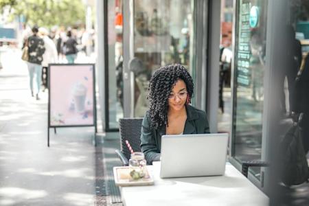 A woman on her laptop outside of a coffee shop