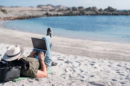 Man working on a laptop at the beach, embodying remote work with Splashtop's flexible access