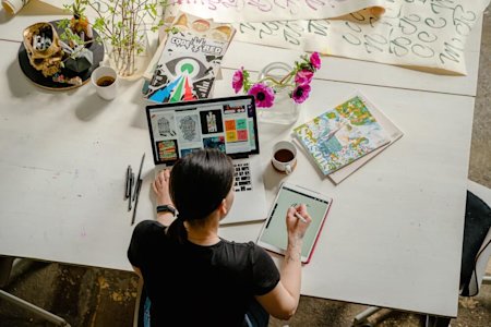 A graphic designer works on a stylus tablet while accessing a workstation remotely using Splashtop.