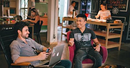 A group of coworkers in a small business office working and smiling.