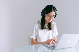 A woman wearing headphones and using Splashtop on her laptop to work remotely.