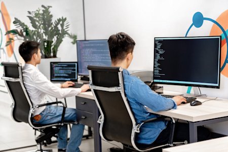 Two co-workers at their desks working on their computers.