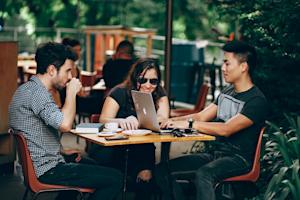 Three professionals collaborating at an outdoor café using Splashtop for efficient workflow