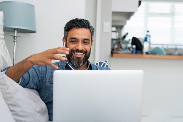 Man on couch smiling while using Splashtop remote access via laptop for efficient remote work