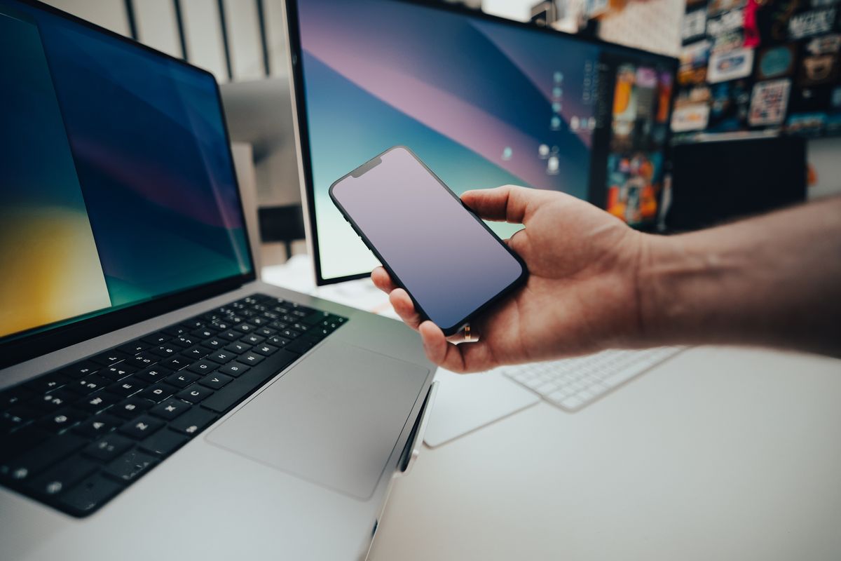 Computers and a mobile device on an office desk.