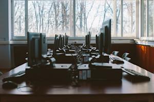 Several computers on a long table in an office.