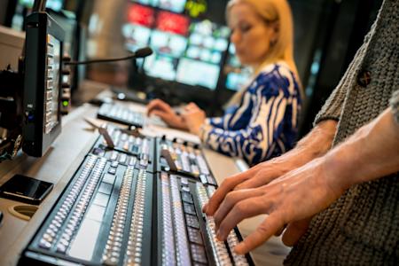 A broadcasting professional typing in a studio room.