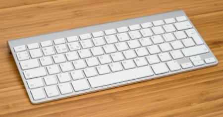 A bamboo desk with a white Apple keyboard resting on it