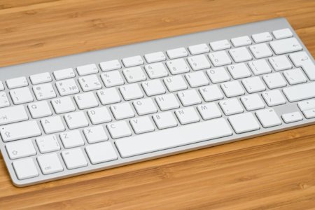 A bamboo desk with a white Apple keyboard resting on it