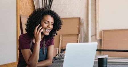 Woman talking on a cell phone while using a laptop
