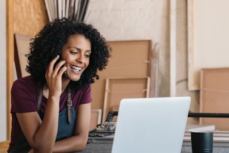 Woman talking on a cell phone while using a laptop