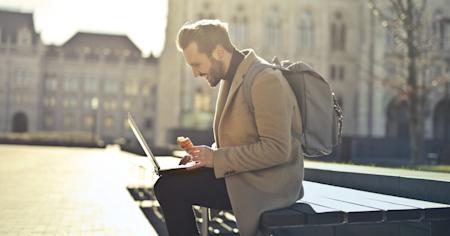 A man sitting outside and working remotely on a laptop.