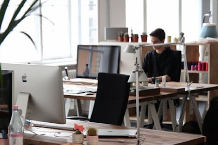 Technician in studio working at computer station reading remote work policy