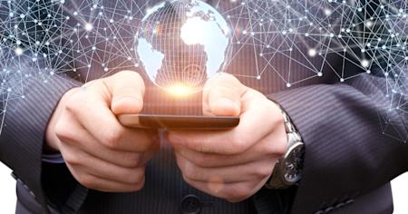 Business professional holding a mobile device with a digital globe and connected network overlay, representing Enterprise Mobility Management (EMM).