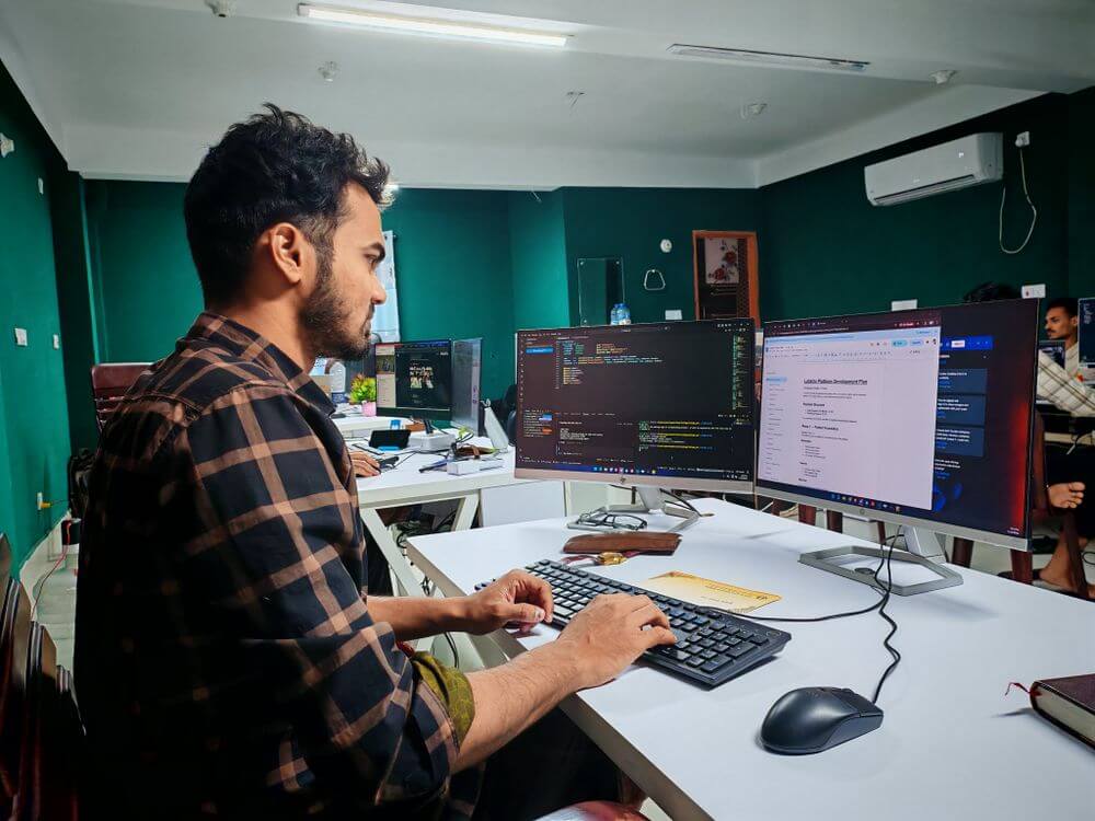 A man working on a computer with code on-screen in an office.