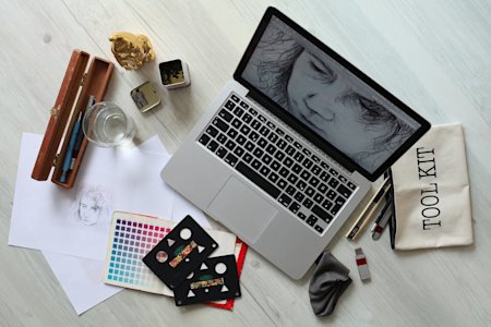 A laptop with graphic design software opened on a desk.