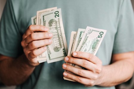 A person holding the money they saved by choosing Splashtop instead of settling for LogMeIn Pro's high pricing