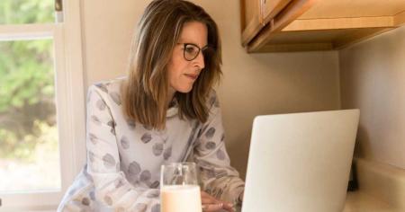 Focused female business owner on a laptop, actively seeking to swiftly implement a Work From Home policy