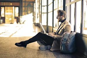 A man sitting and using his laptop to remotely access his Ubuntu desktop.