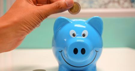 A person puts a coin inside a piggy bank