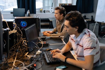 Two IT techs sitting at desks in an office and using computers.