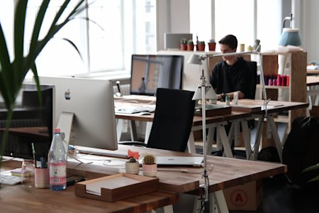 An office with several Mac workstations on desks.