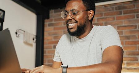 A smiling person working on a computer.