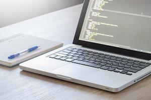 A laptop and notebook on a desk.