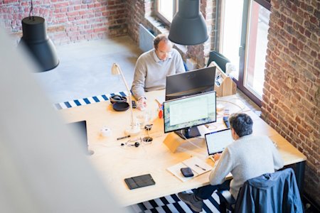 Coworkers on their computers at their desks in an office.