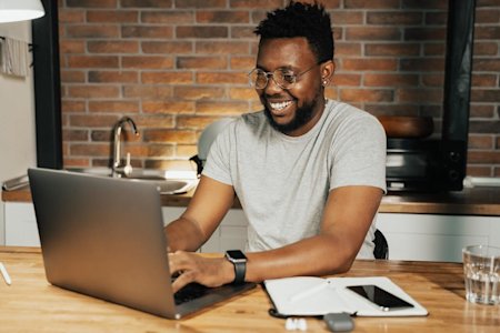 Man with glasses working productively on a laptop in a modern kitchen using Splashtop
