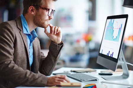 IT professional analyzing data on a computer screen, illustrating the importance of Remote Monitoring and Auditing for effective Remote Support.