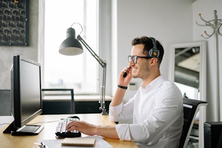 An IT service desk technician at their computer providing remote support to an end user.
