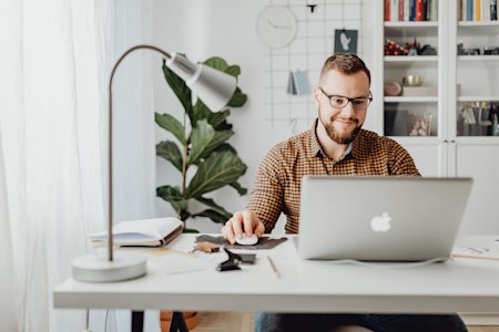 A man sitting at a desk using his laptop.
