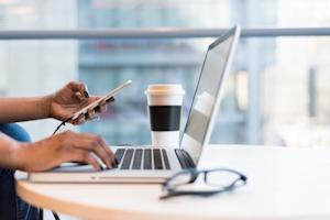 A person using a laptop and smartphone.