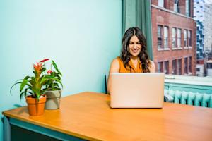 A happy woman sitting at a table using Splashtop on her laptop