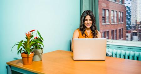 A happy woman sitting at a table using Splashtop on her laptop