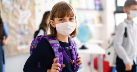 Young girl wearing a protective face mask while attending school as a precaution against Covid-19