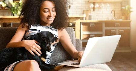 Woman sitting on a couch with her dog using a laptop