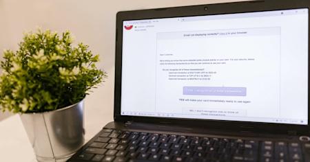 A black laptop sitting on a table displaying an email message regarding fraudulent behavior.